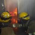 Two firefighters practice fire suppression from the interior.
